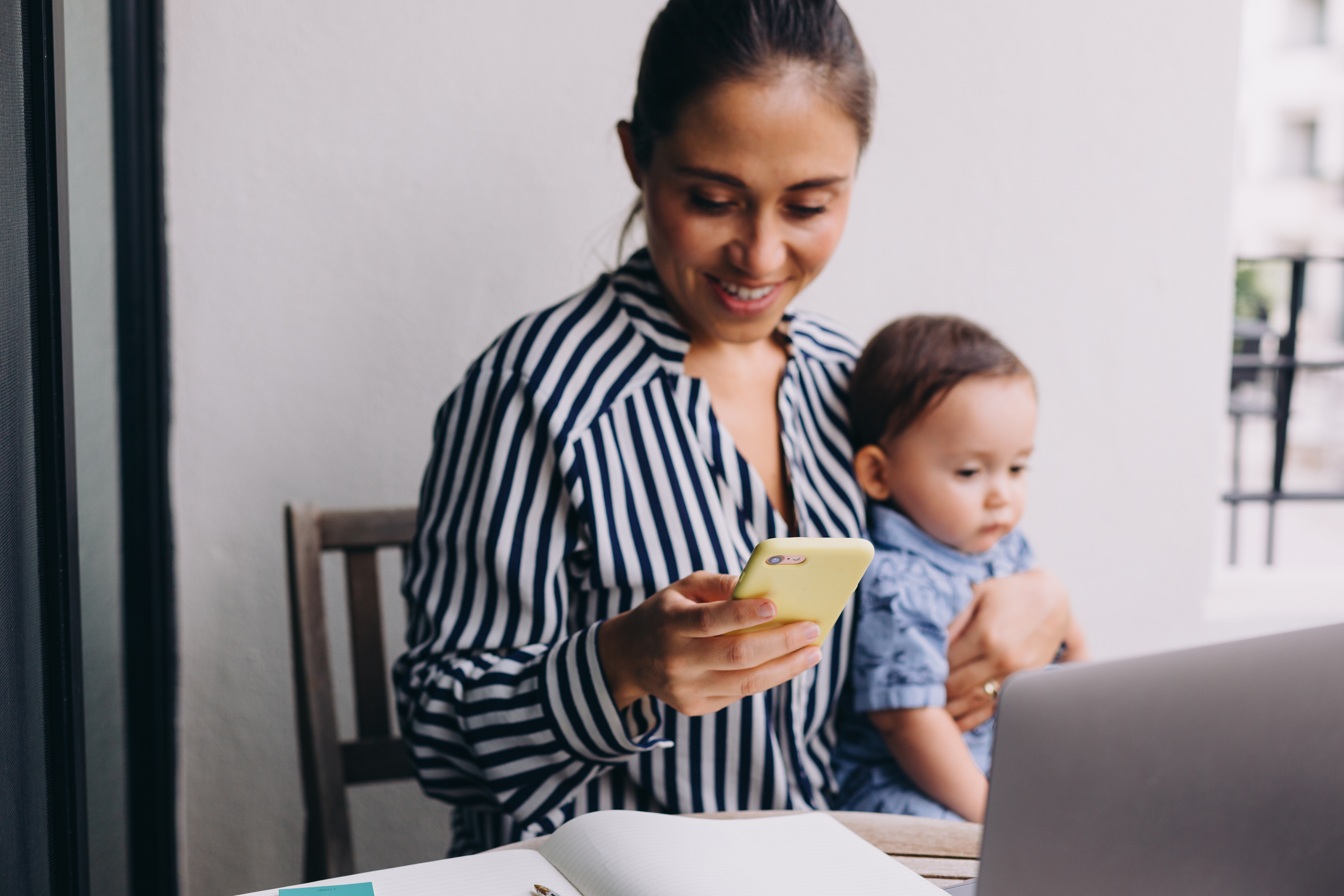 Woman Sitting Using Phone Baby On Lap