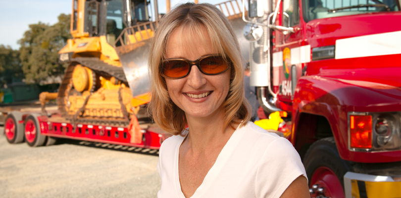 Heather Huerta smiling in front of construction vehicles