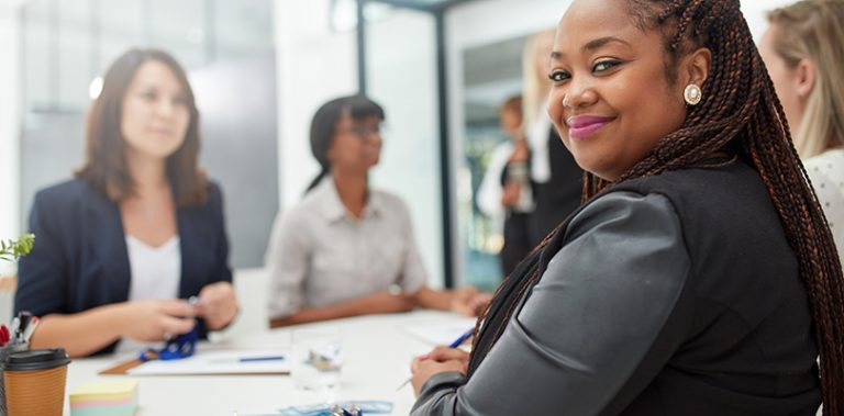 Smiling CalPERS employer in a meeting with coworkers.