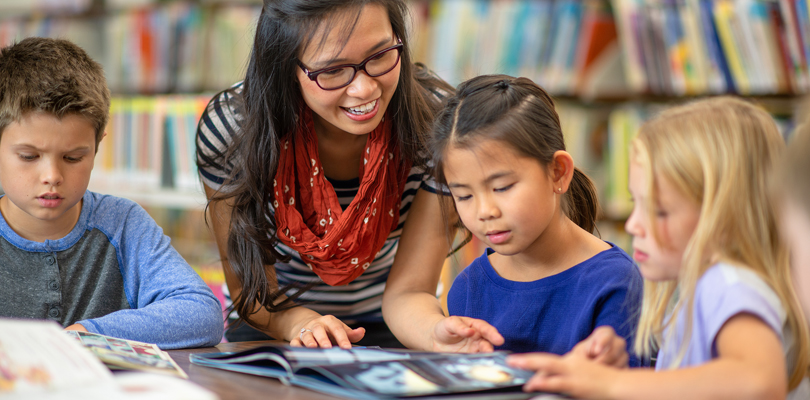 Teacher reading to children in library