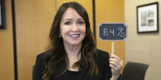 Marcie Frost, CEO of CalPERS, holding a small sign that reads ‘84%