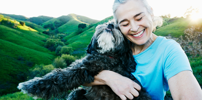 Older woman with gray hair, wearing blue t-shirt, with black and white fluffy dog.