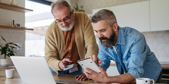 Father and son in kitchen using laptop computer
